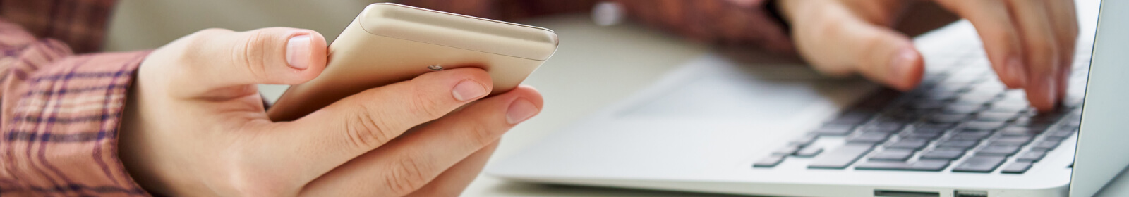 Person checking phone while using a laptop.